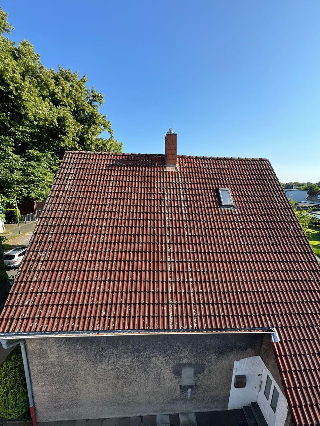 Frisch gereinigtes, leuchtend rotes Ziegeldach unter blauem Himmel